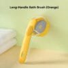 pet-bath-brush-34-2 long handle pet bath brush orange full overall product shot placed on light countertop stacked white towel beside transparent liquid storage chamber visible