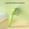 pet-bath-brush-34-4 long handle pet bath brush green full overall product display shot against light green wall hanging hole on end of ergonomic handle transparent shampoo tank section
